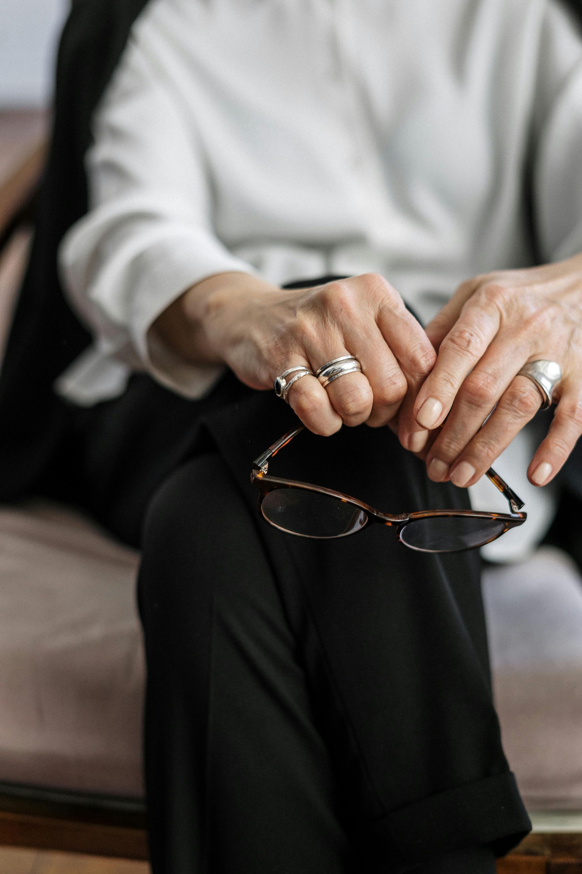 Una mujer está sentada en un sofá sosteniendo un par de gafas.