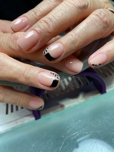Un primer plano de las uñas de una mujer con una manicura francesa negra.