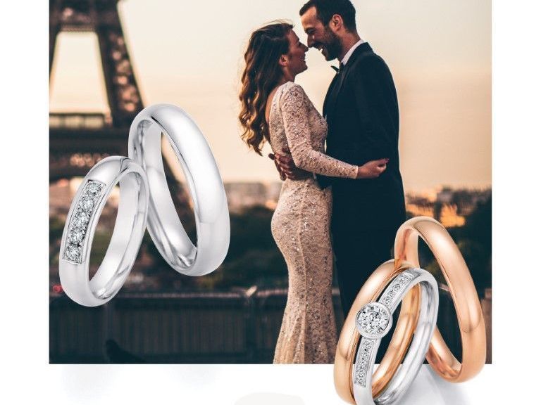 Brautpaar vor Eiffelturm und silber- und goldfarbene Trauringe