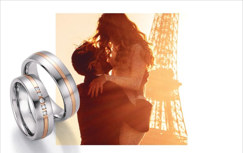 Brautpaar vor Eiffelturm und silber- und goldfarbene Trauringe