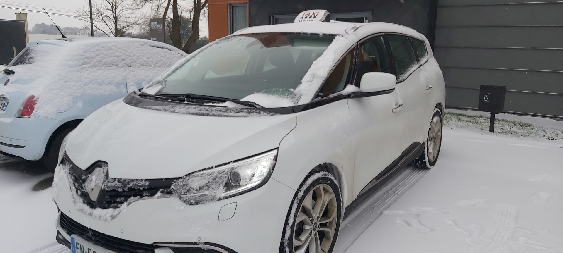 Taxi blanc de marque Renault sous la neige
