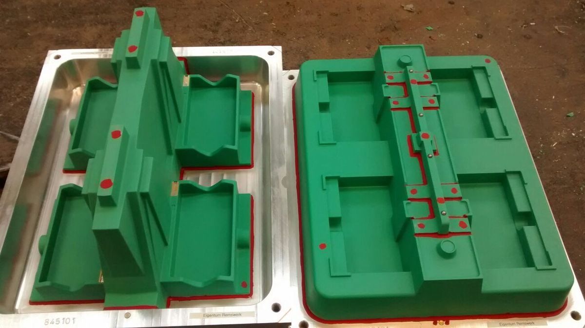 Zwei grüne Plastikformen liegen nebeneinander auf einem Tisch.