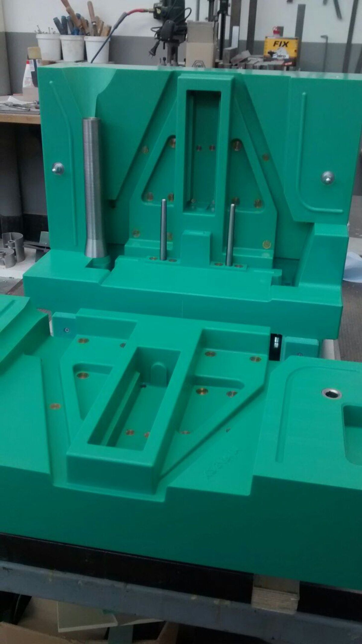 Eine grüne Kunststoffform steht auf einem Tisch in einer Werkstatt.