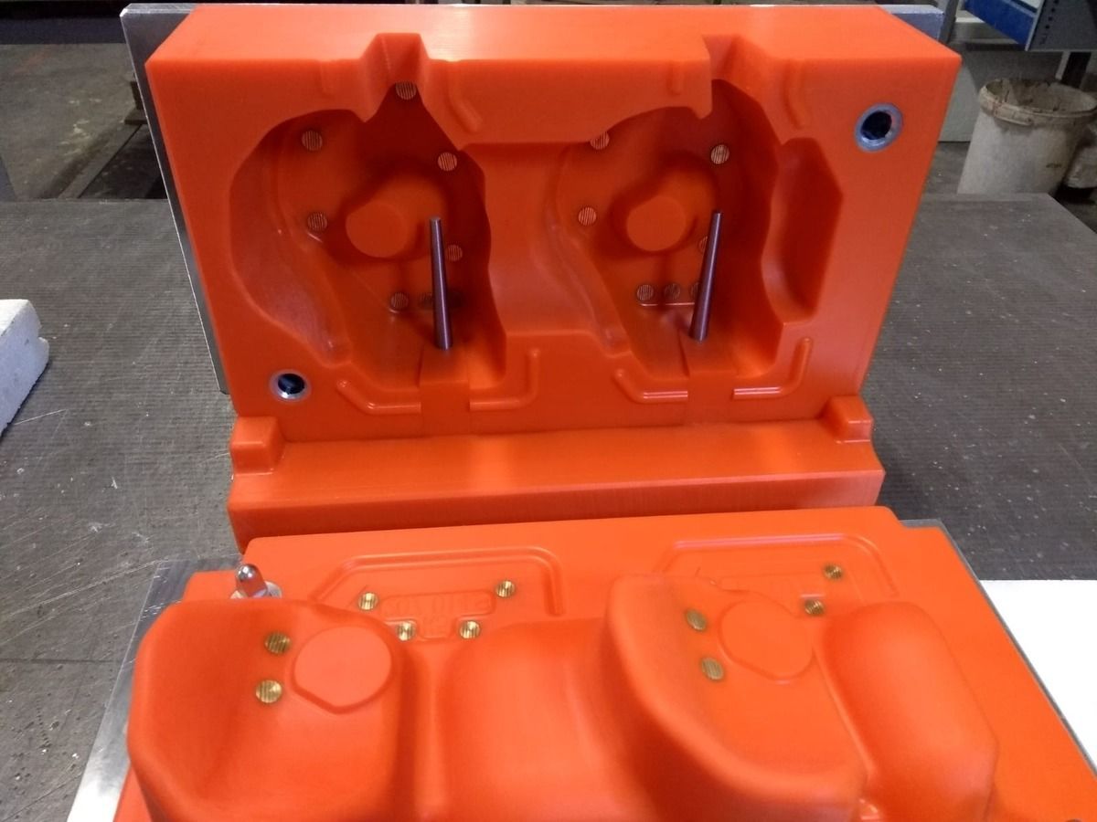 Eine orange Kunststoffform mit einem Loch in der Mitte liegt auf einem Tisch