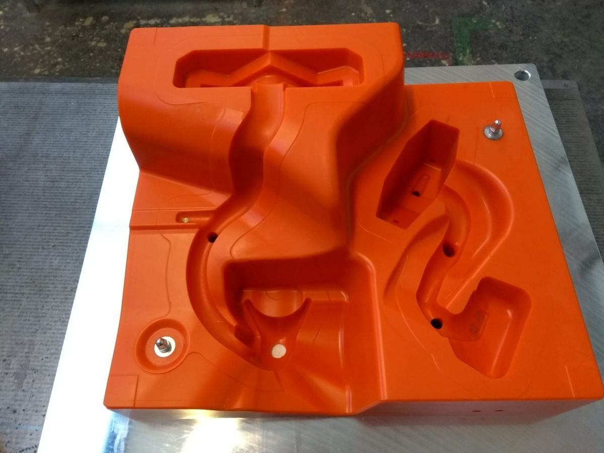 Ein großes orangefarbener Prototyp mit Löchern darin liegt auf einem Tisch