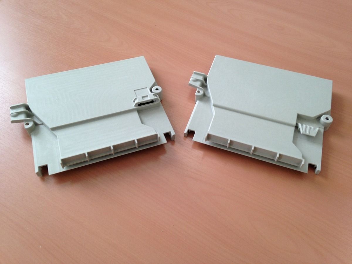 Auf einem Holztisch liegen zwei Plastikstücke.