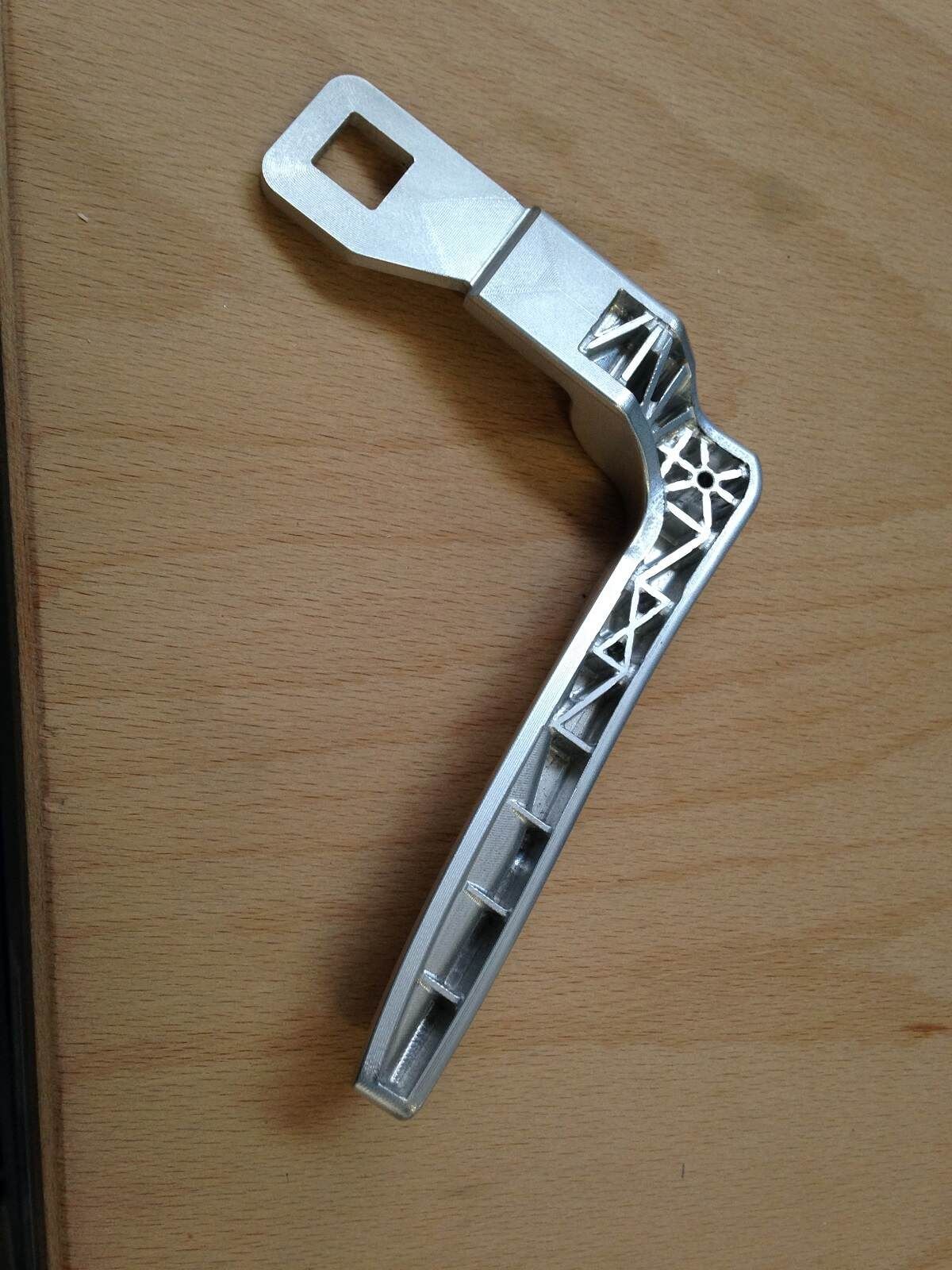 Auf einem Holztisch liegt ein Metallgriff.
