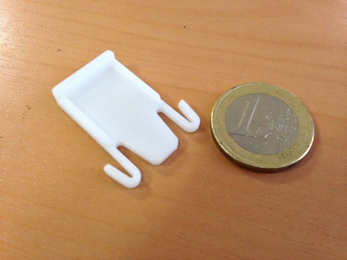 Ein weißer Plastikhaken neben einer 1-Euro-Münze