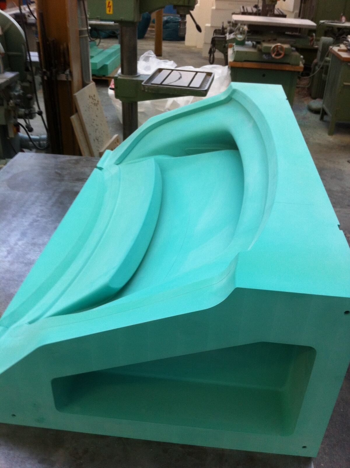 Ein grünes Stück Schaumstoff liegt auf einem Tisch in einer Werkstatt