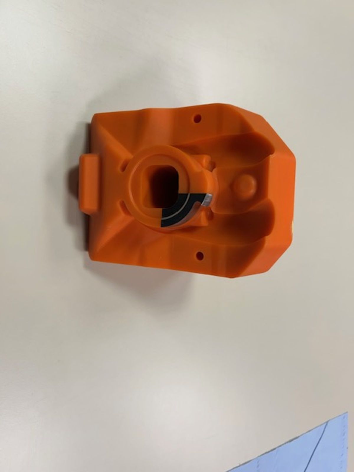 Ein kleiner orangefarbener Prototyp liegt auf einer weißen Oberfläche