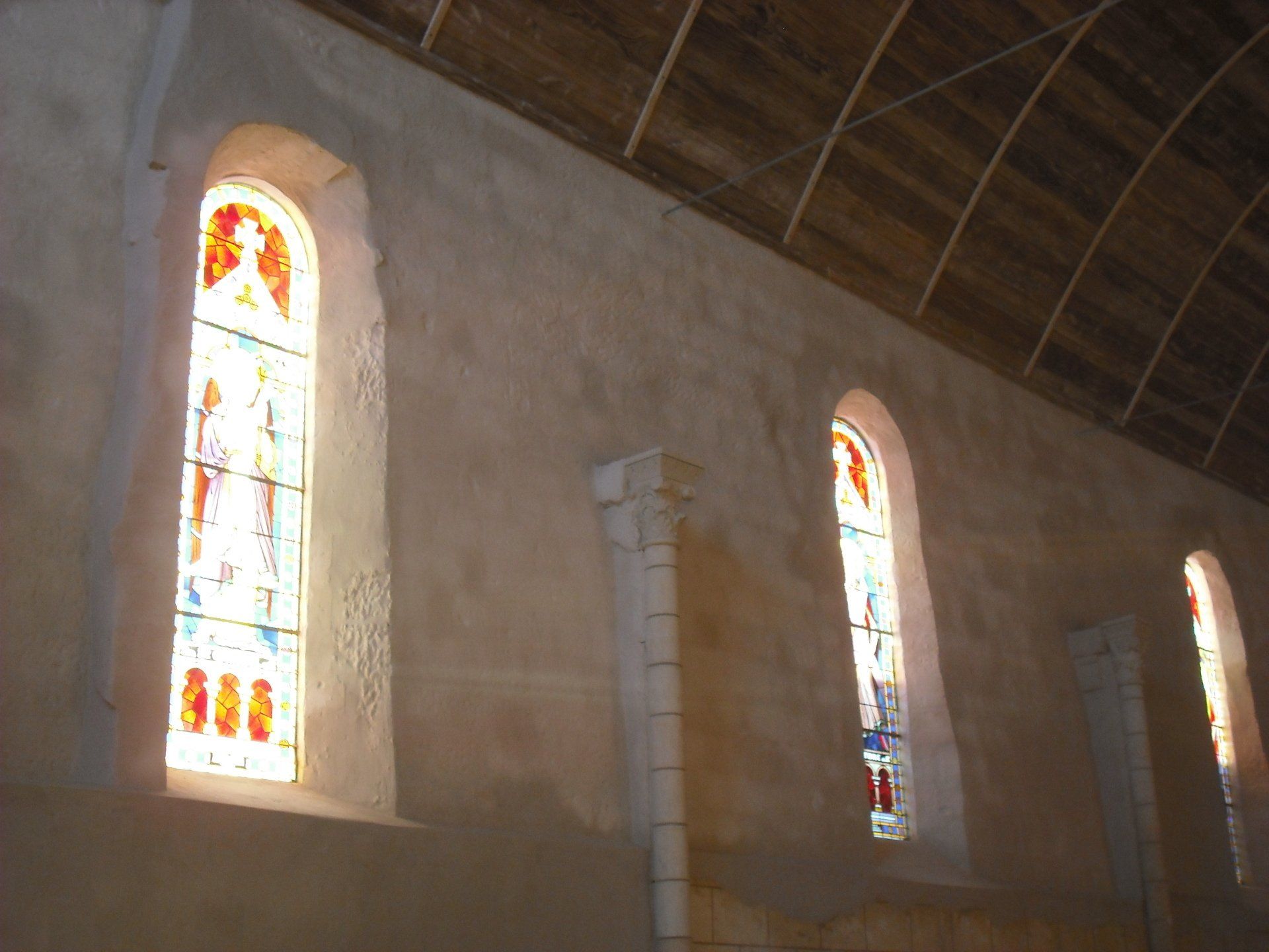 Intérieur d’une église avec de hauts vitraux et un plafond en bois élevé