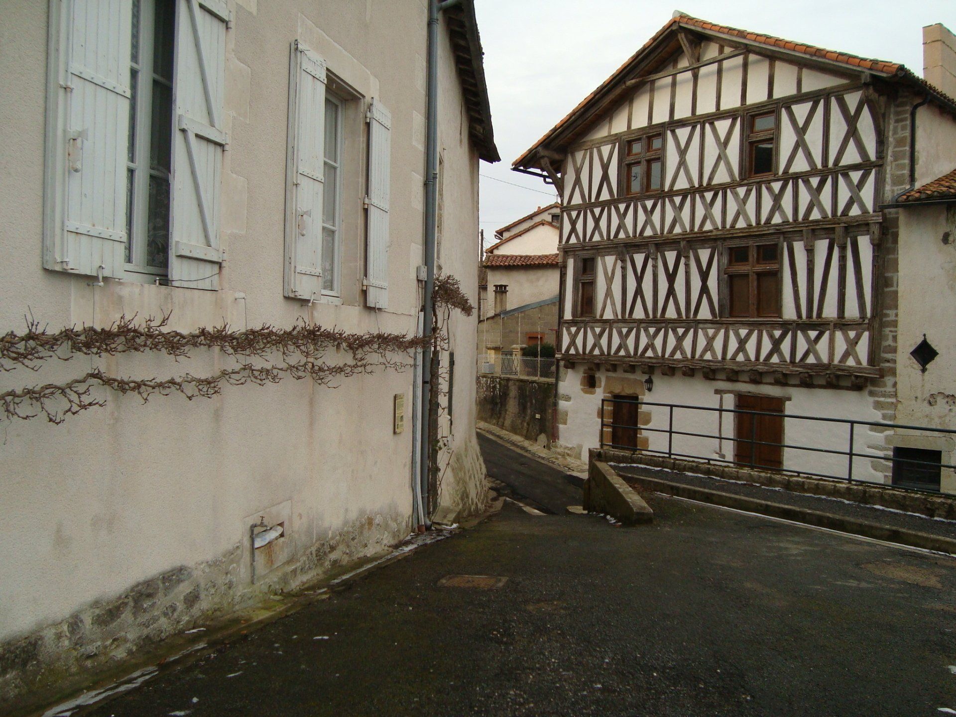 Rue étroite entre des maisons blanches en stuc et à colombages, par temps nuageux