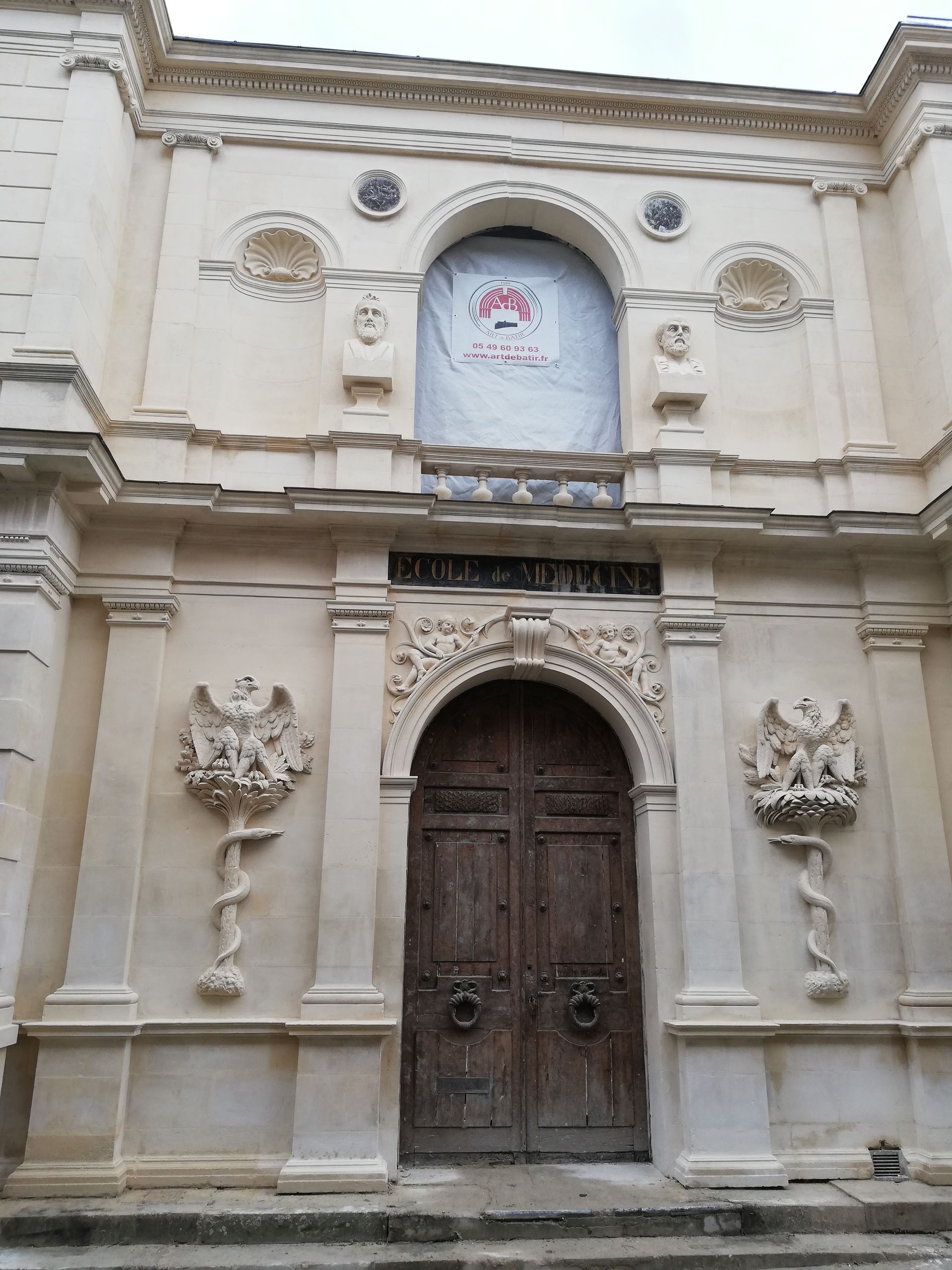 Façade ornée en pierre, avec une porte cintrée en bois sculpté et des reliefs floraux décoratifs