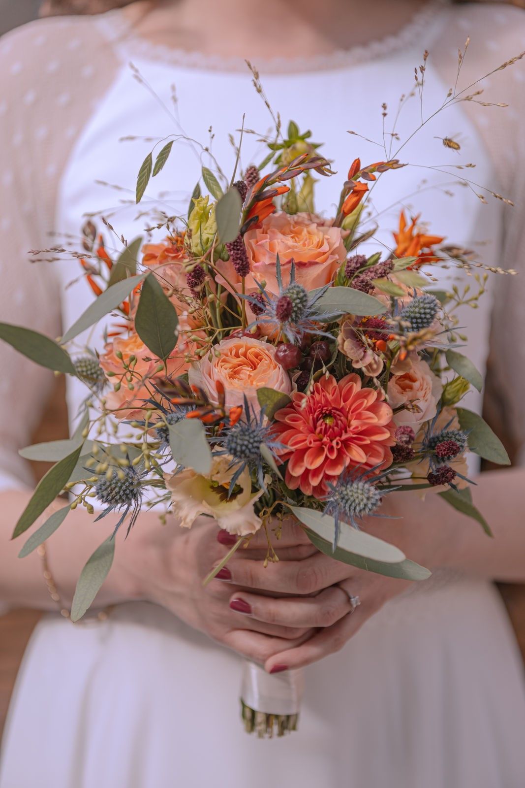 Eine Frau in einem weißen Kleid hält einen Blumenstrauß.