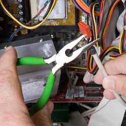 Persona que utilitza unes alicates per treballar en el cablejat intern d'un ordinador.