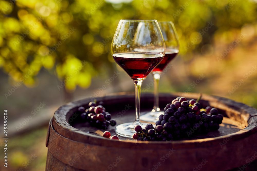 Deux verres de vin rouge et de raisins sur un tonneau en bois.