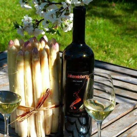 Une bouteille de vin est posée sur une table à côté d'un vase d'asperges