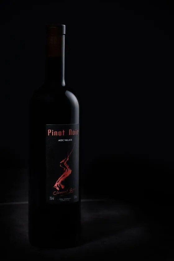 Une bouteille de vin pinot noir est posée sur une table noire.