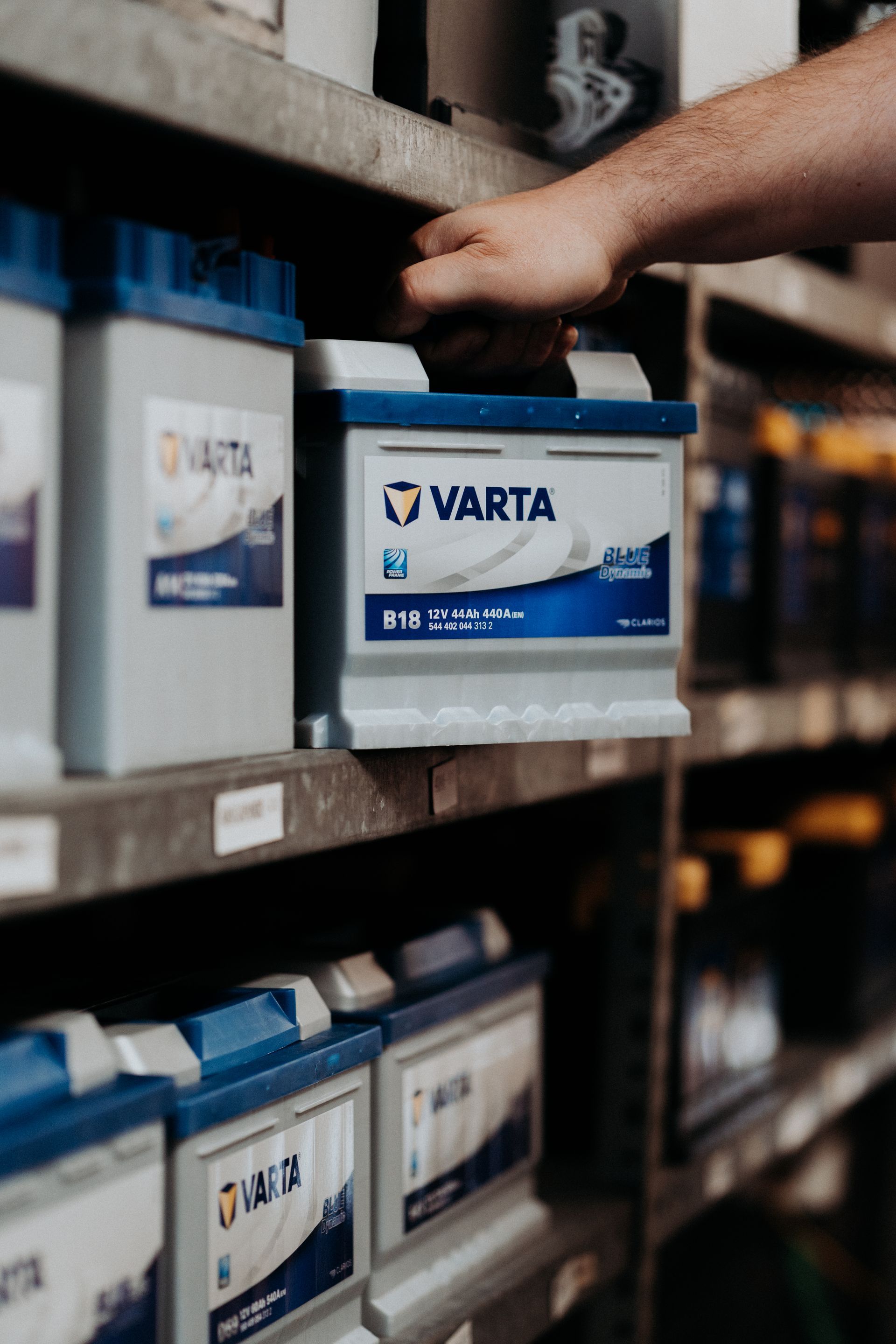 Eine Person nimmt eine Varta-Batterie aus einem Regal.