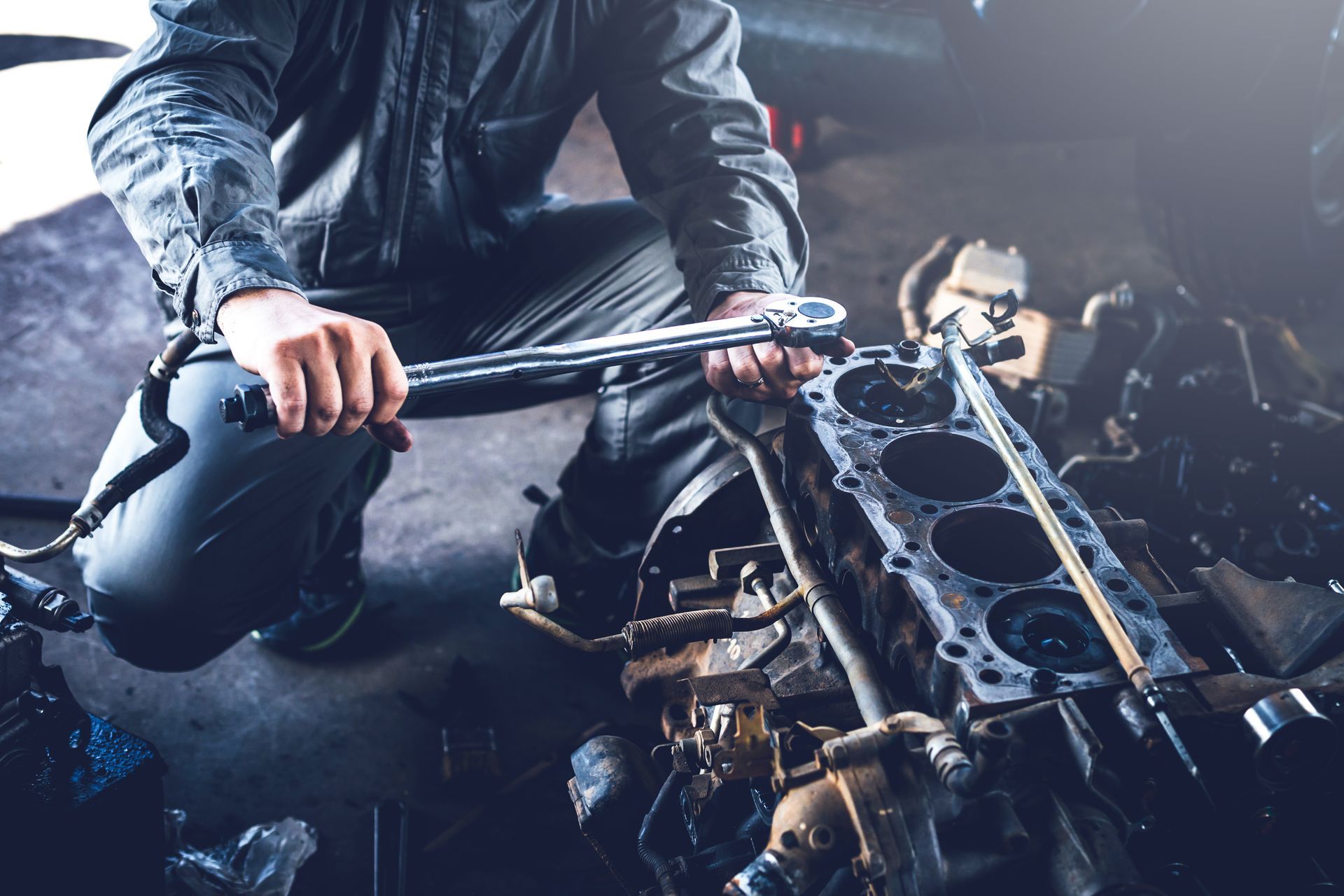 Un mécanicien utilise une clé pour réparer le moteur d'une voiture dans un garage sombre.