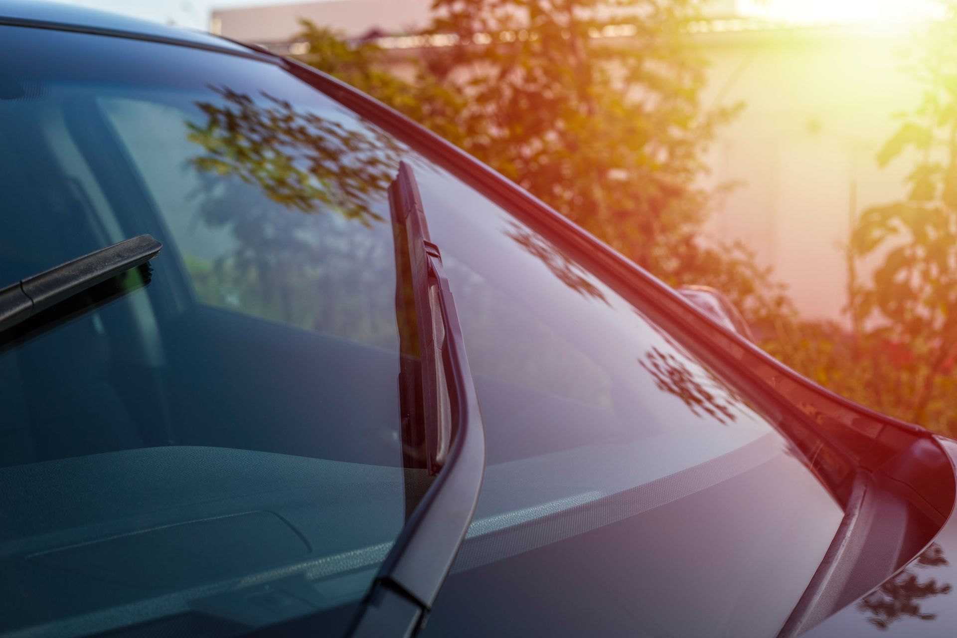 Gros plan sur le pare-brise d'une voiture, la lumière du soleil se reflétant sur le verre.