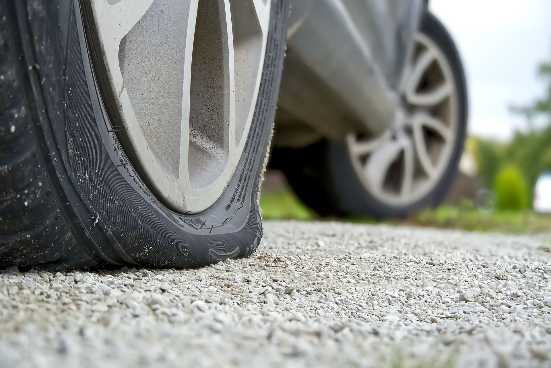 Pneu avant crevé sur une voiture garée en bord de route.