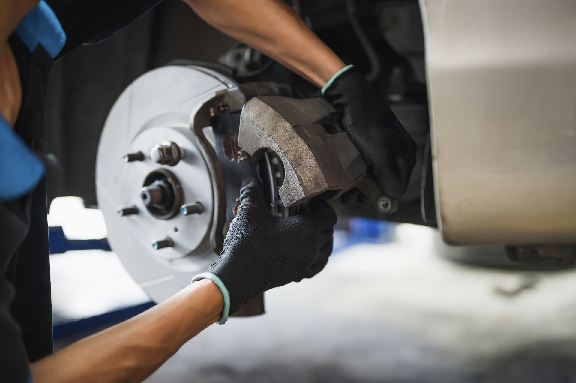 Un mécanicien installe un disque de frein de voiture avec des gants dans un atelier de réparation.