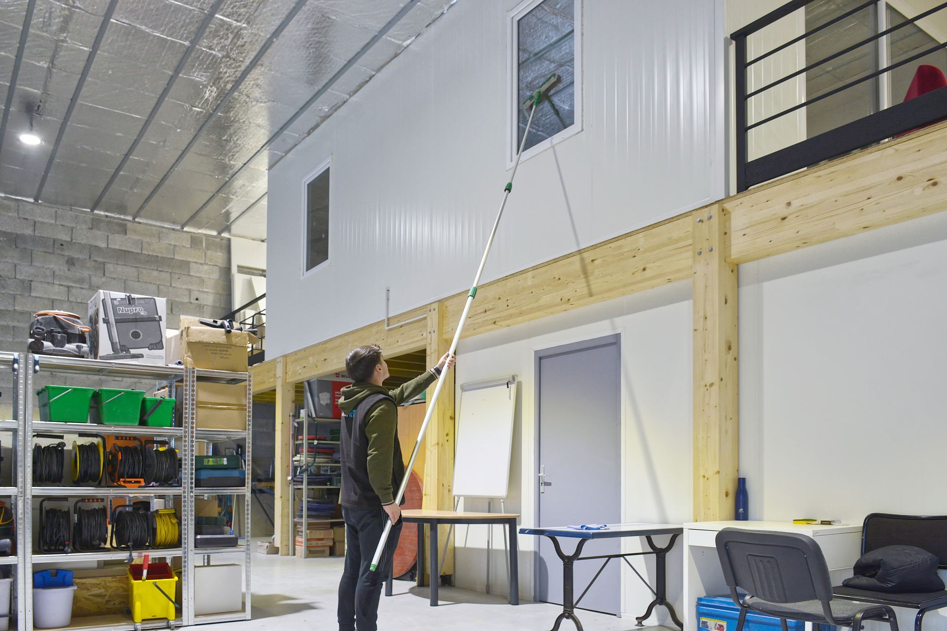 Homme nettoyant des vitres en hauteur.