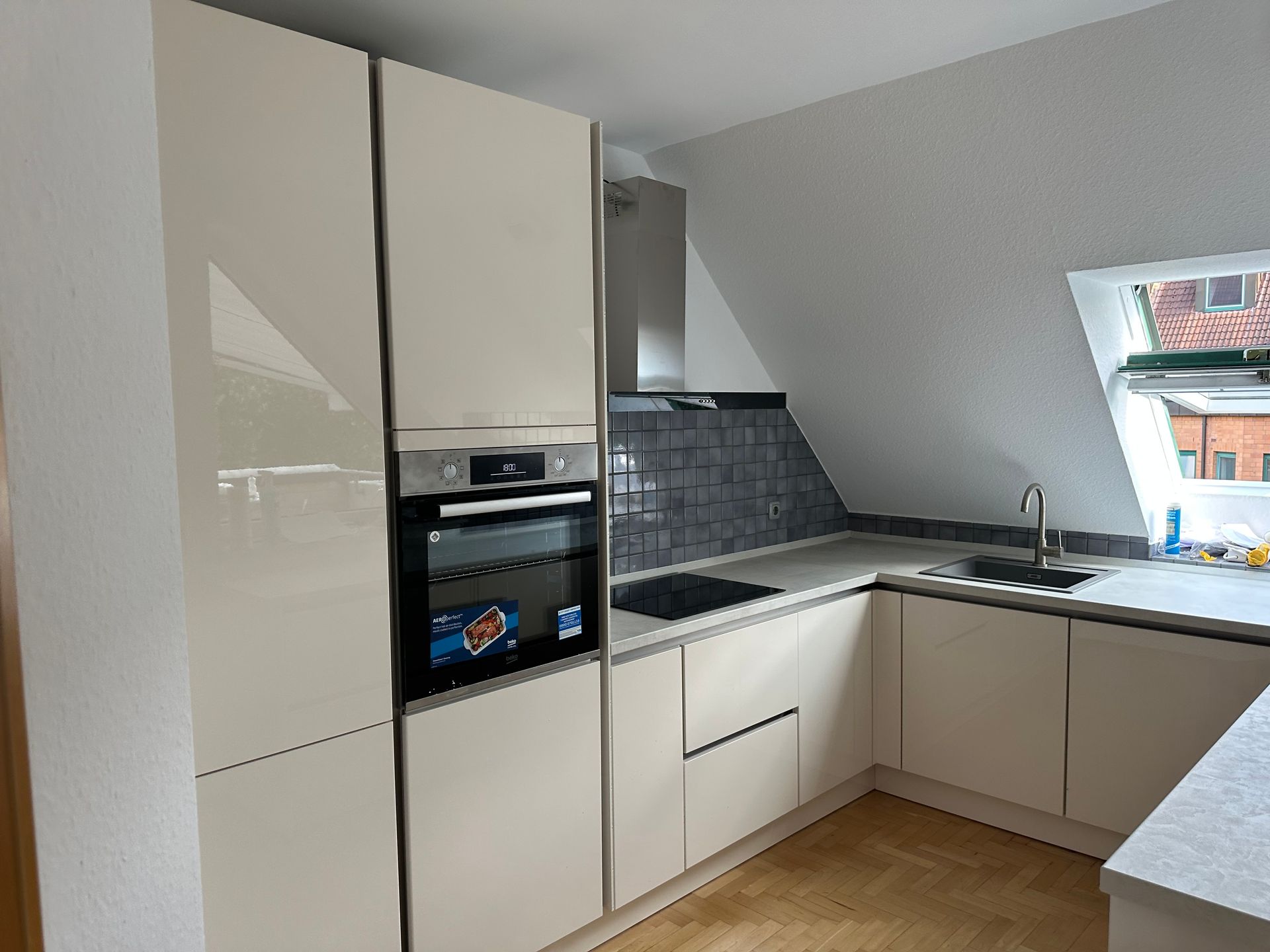 Eine Küche mit weißen Schränken, einem Ofen, einem Spülbecken und einem Fenster