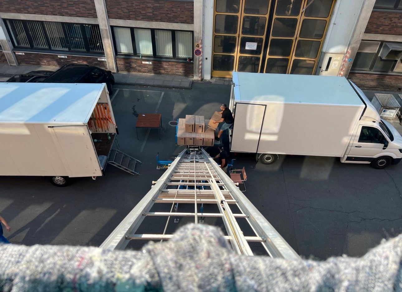 Mitarbeiter transportieren Möbel aus einem LKW auf einen Möbelaufzug