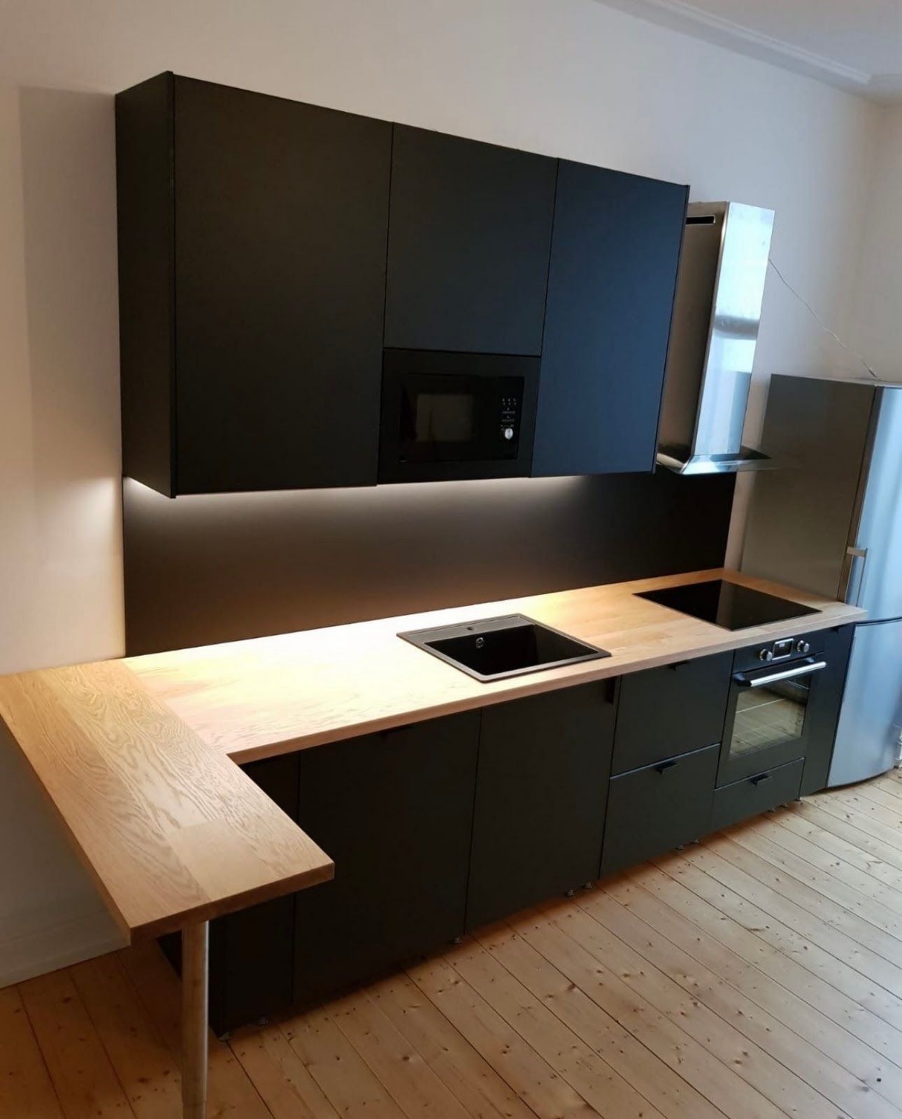 Eine Küche mit schwarzen Schränken und einer kleinen Arbeitsfläche