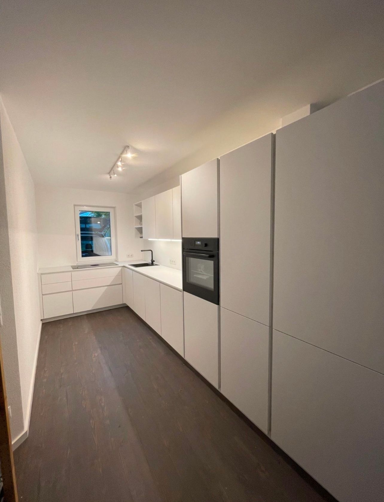 Eine Küche mit weißen Schränken und einem Einbauofen