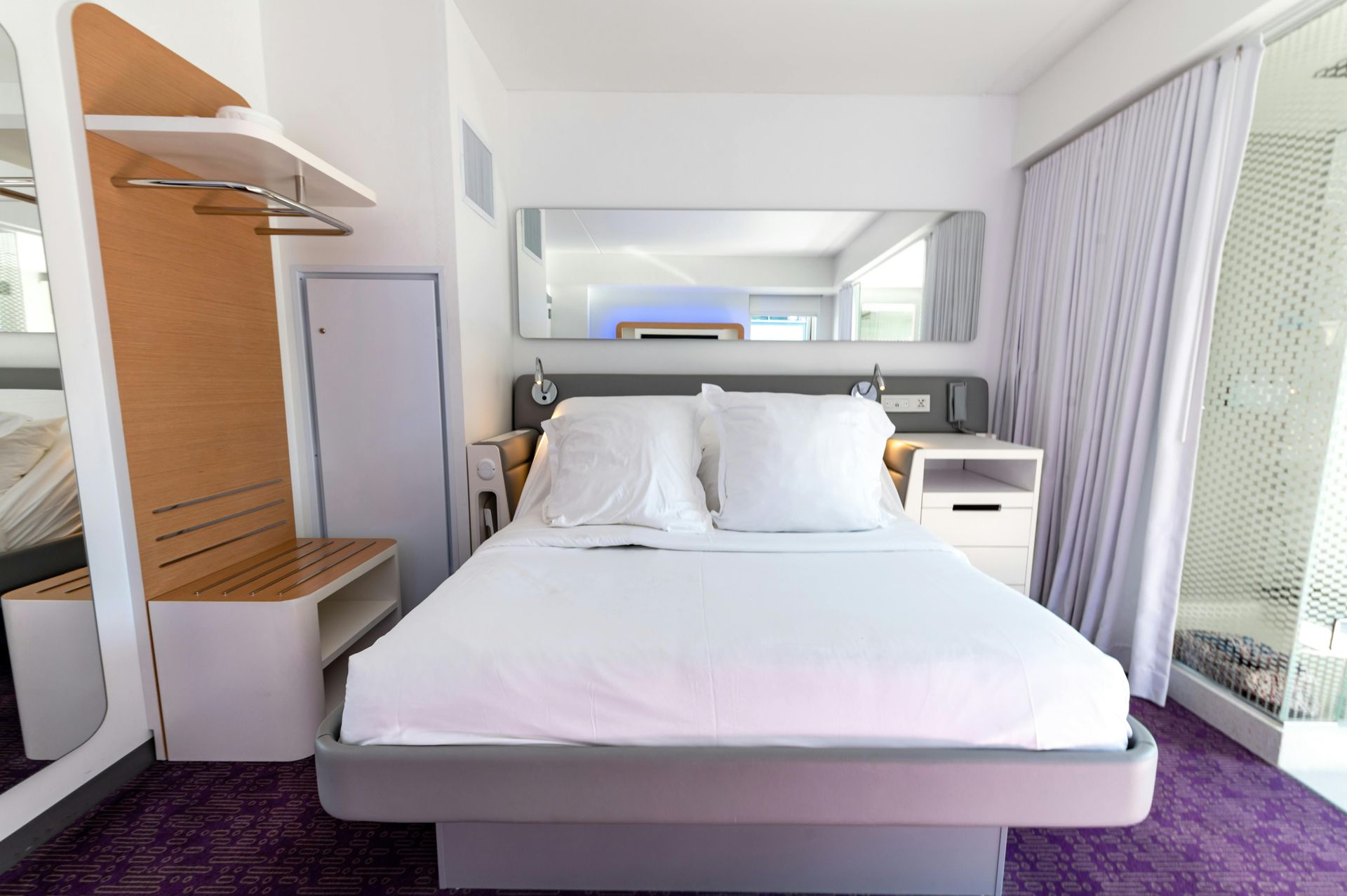 A hotel room with a large bed and a purple carpet.