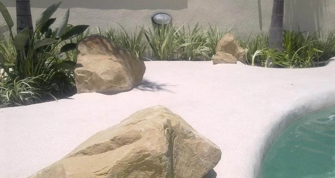 Una gran roca está al lado de una piscina.