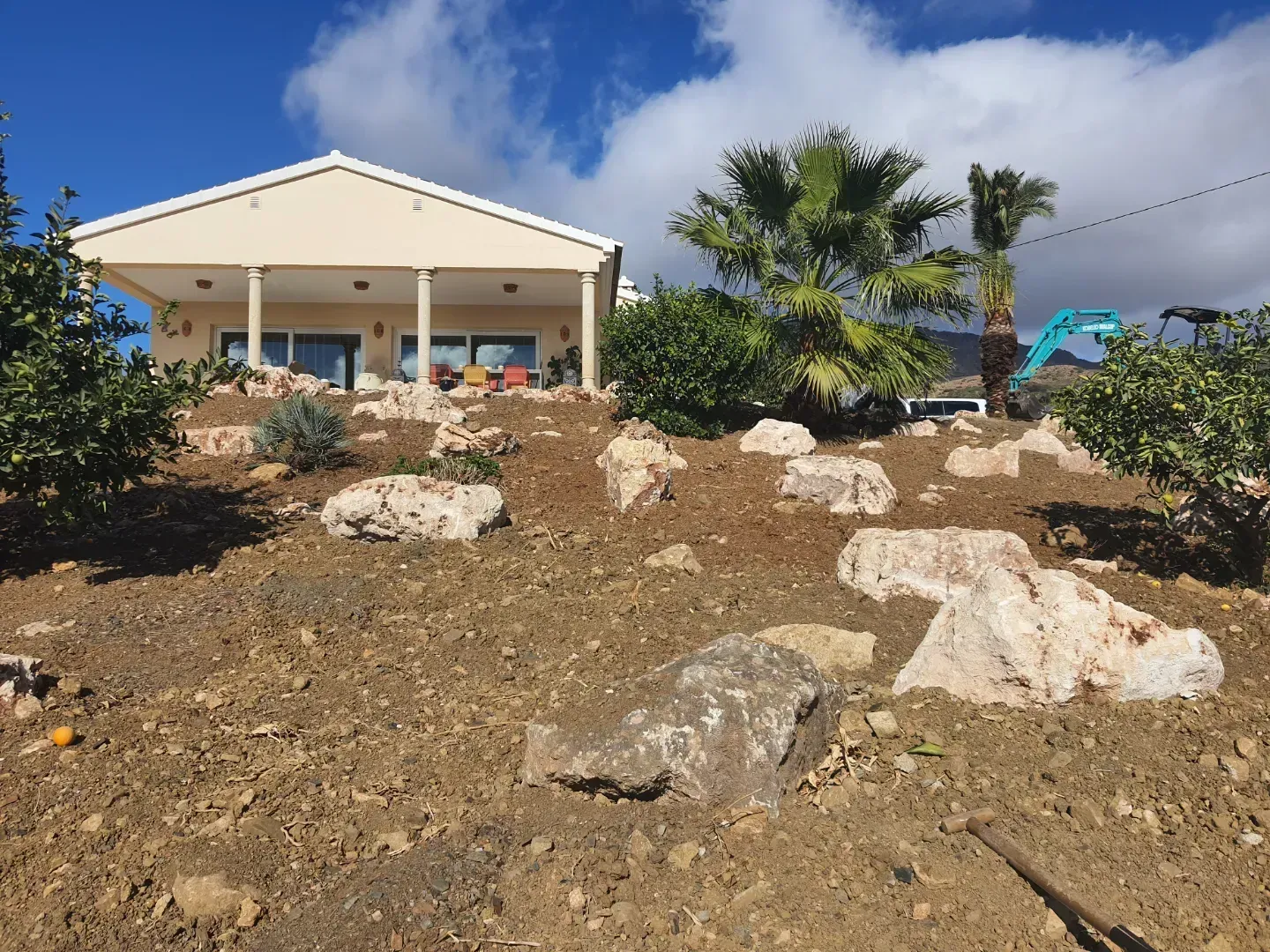 Una casa situada en la cima de una colina con rocas delante.