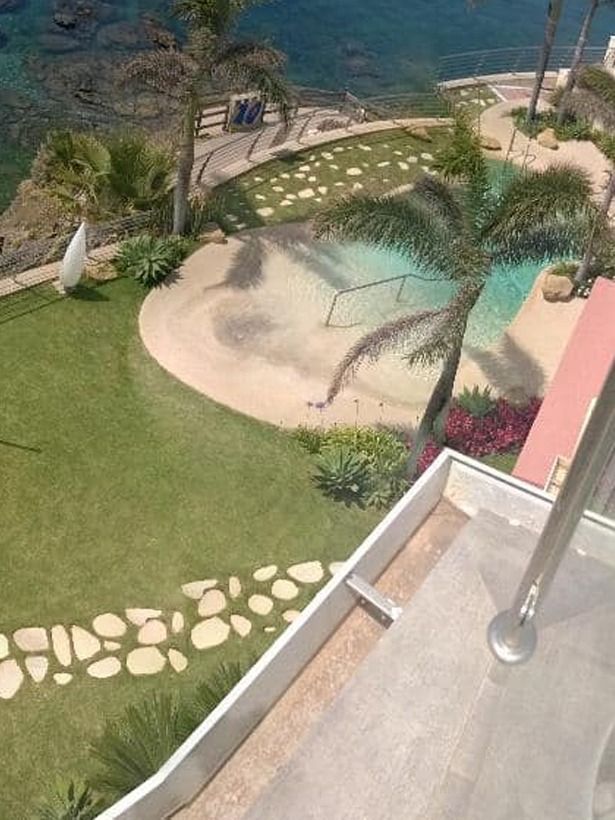 Una vista de una piscina desde un balcón con vista al océano.