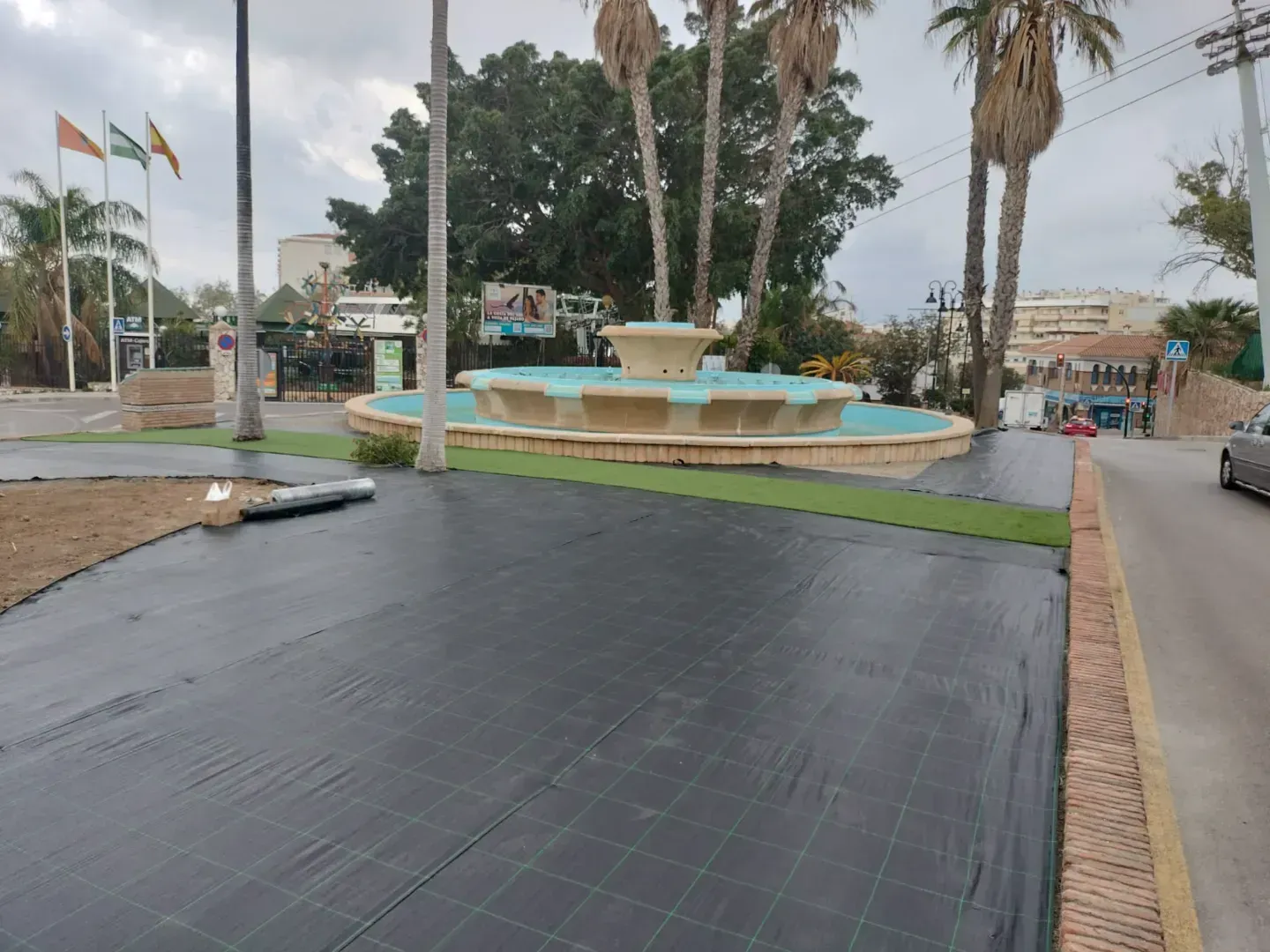 Una fuente en medio de una calle con palmeras al fondo.