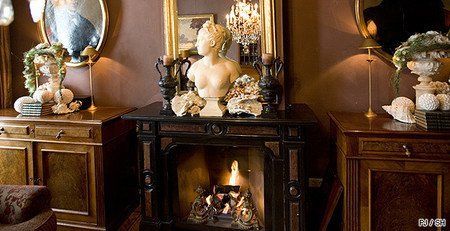 Cheminée encadrée de meubles en bois sombre, de miroirs ornés et d'un buste décoratif. Intérieur chaleureux et éclairé.