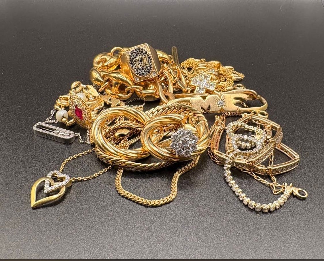 Un tas de bijoux en or : bagues, chaînes et bracelets sertis de diamants, sur une surface sombre.