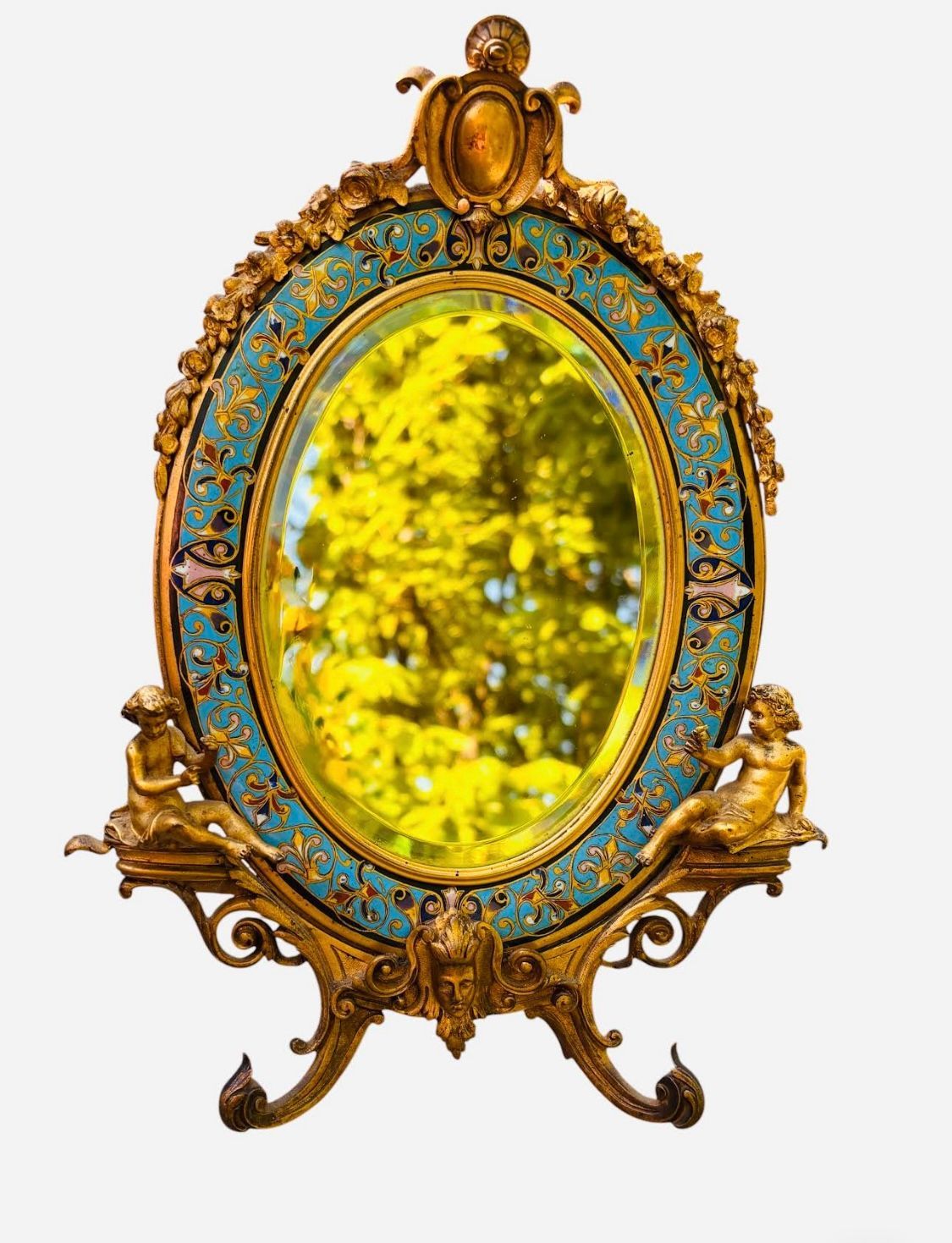 Miroir ovale orné d'or et de turquoise, avec des accents de chérubins et un reflet de feuillage.