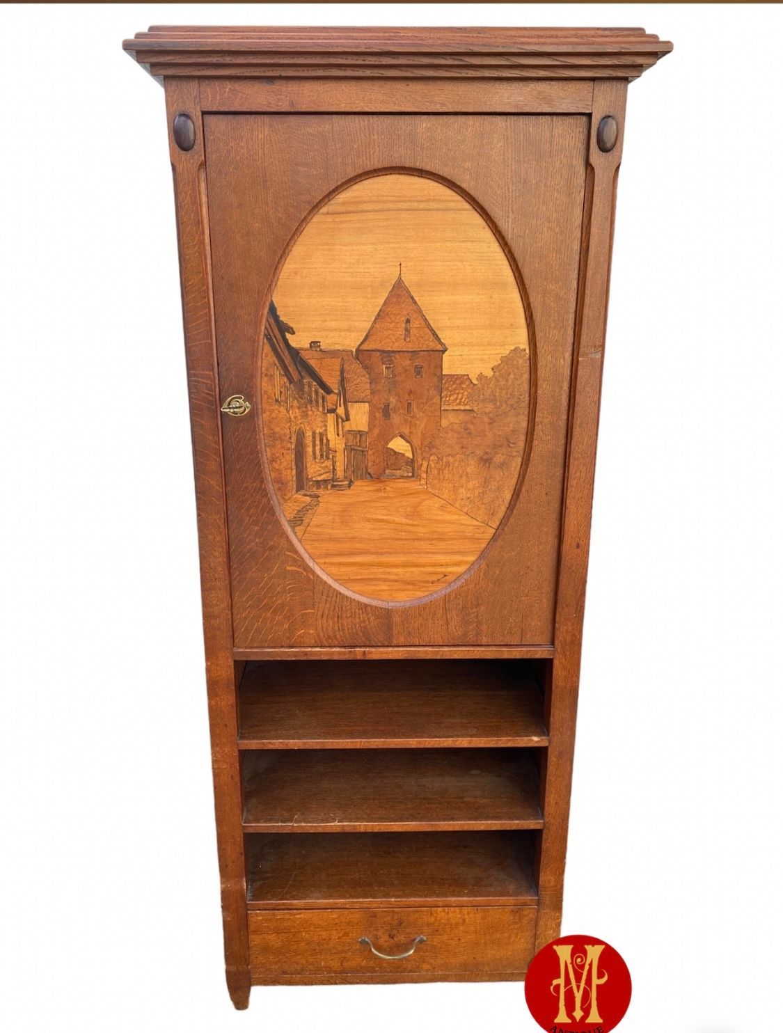 Armoire en bois ornée d'une marqueterie ovale représentant une scène de construction, avec étagères et tiroir.