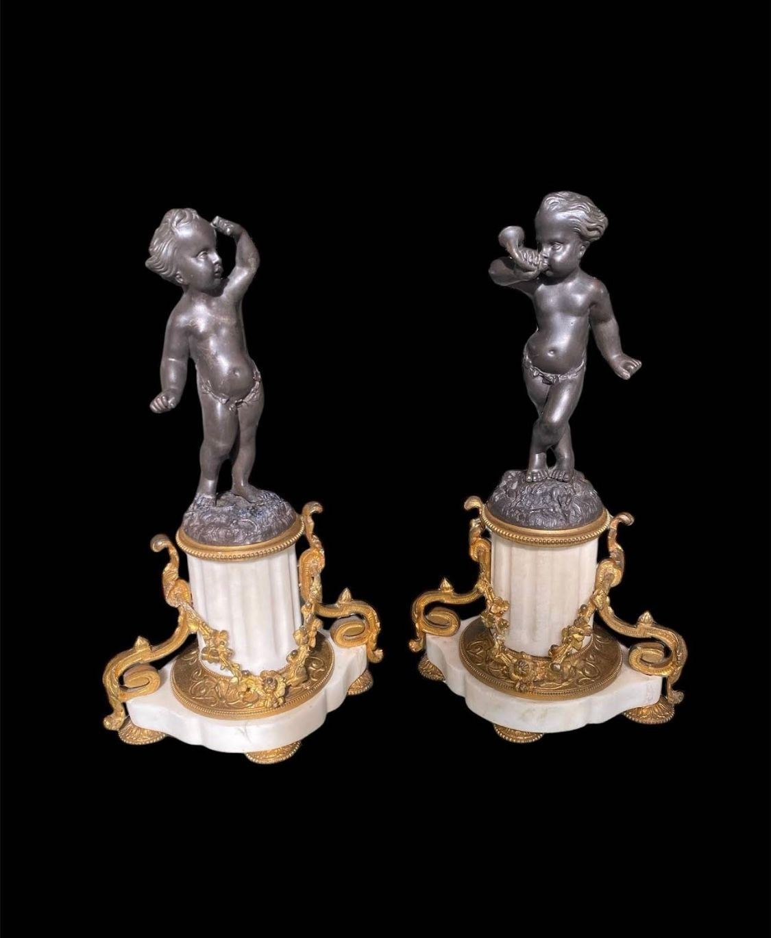 Deux sculptures de figures chérubines sur des piédestaux richement ornés.
