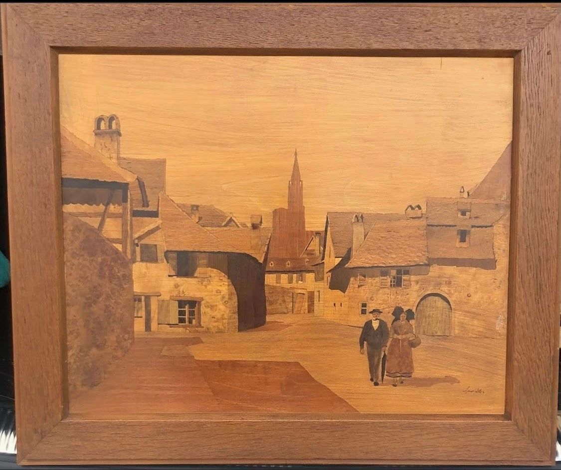 Marqueterie en bois représentant une place de ville européenne avec deux personnages qui marchent, encadrée.