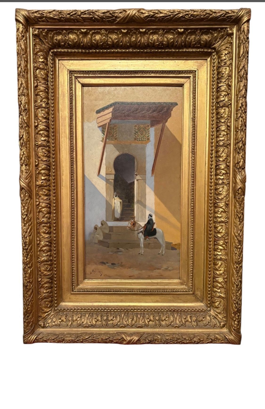 Tableau représentant une porte cintrée avec un personnage assis, encadré d'or orné.