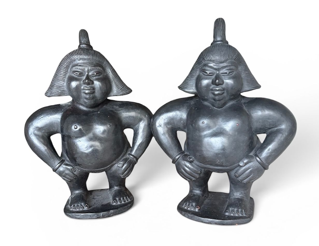 Deux petites figurines asiatiques en argent se tenant côte à côte, les mains sur les hanches.
