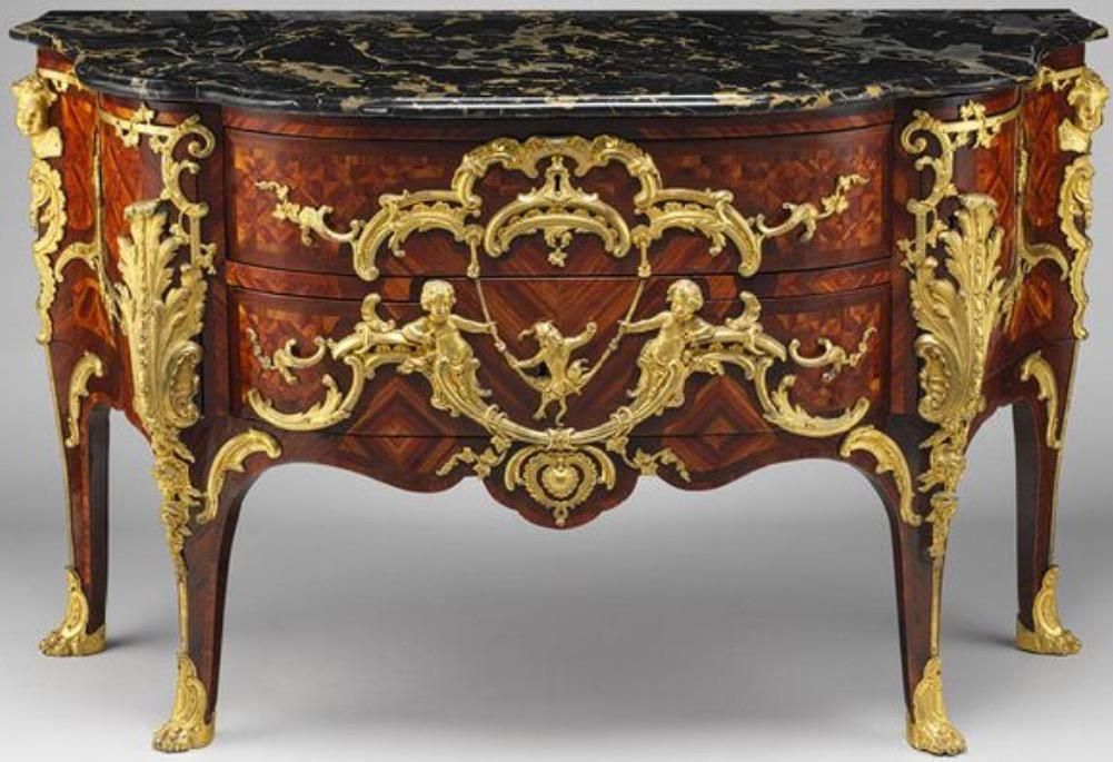 Commode ancienne ornée, avec plateau en marbre foncé, deux tiroirs, ferrures dorées et pieds incurvés.