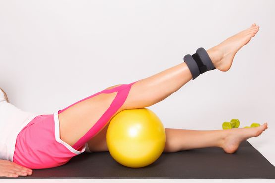 Person macht eine Übung mit einem gelben Gymnastikball