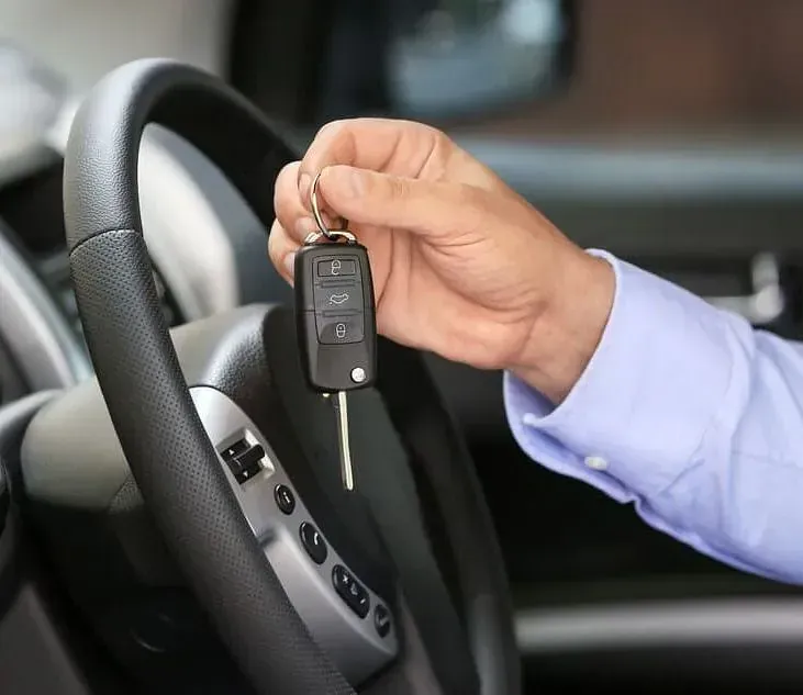 Una persona sostiene una llave de coche en la mano mientras está sentada en un automóvil.
