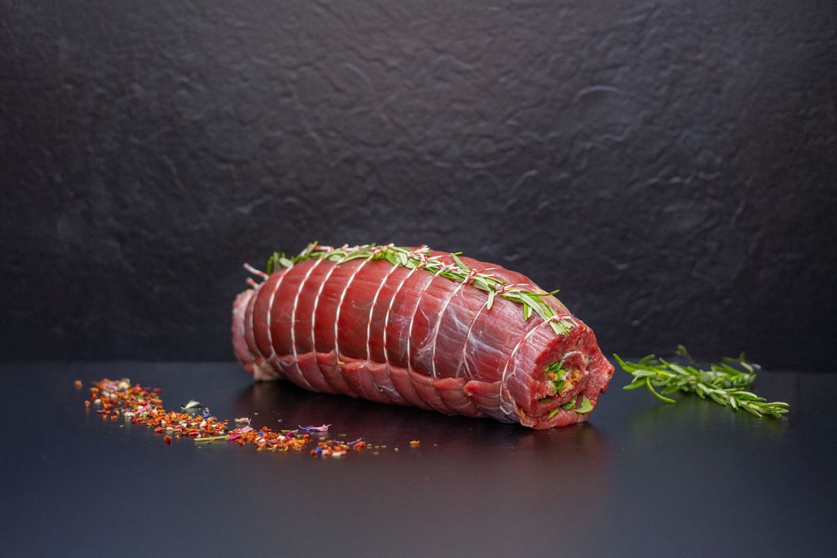 Auf einem schwarzen Tisch liegt ein Stück rohes Fleisch.