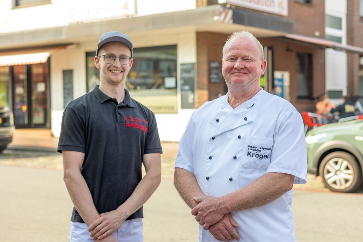 Zwei Männer stehen nebeneinander vor einem Gebäude.